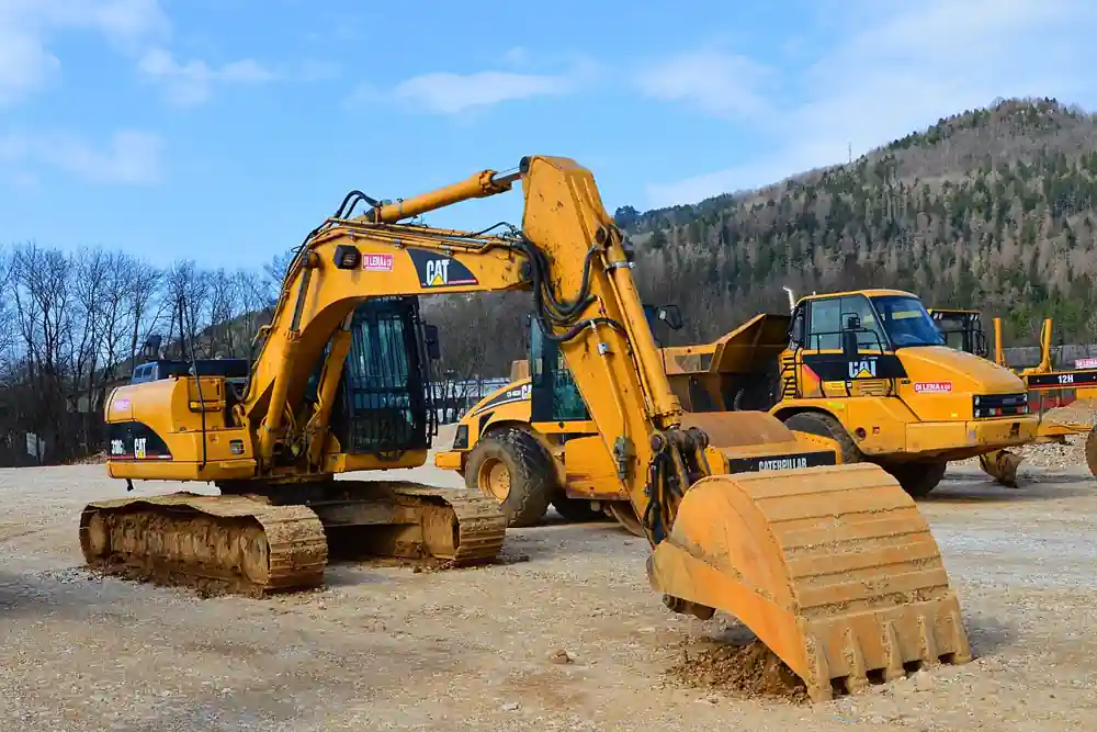 Yellow Caterpillar 318CL crawler hydraulic excavator with steel tracks, rotating upper structure, articulated boom and stick, and a large digging bucket parked on a construction site