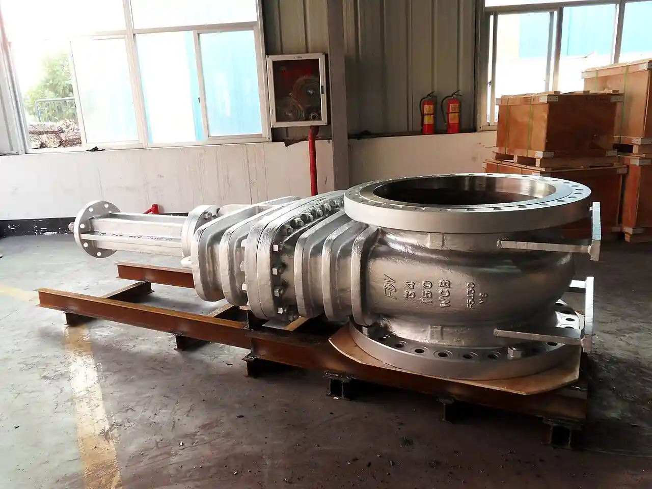 A large flanged cast steel gate valve body with bonnet, resting on a steel skid, showing the WCB cast body markings and full-bore flanged ends