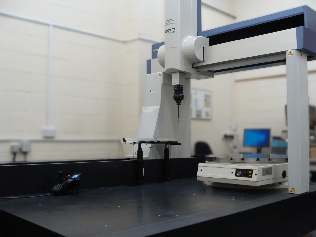 Five-axis scanning coordinate measuring machine with probe head and stylus positioned over a machined part