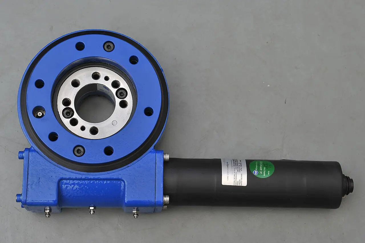 Standard SE-series enclosed worm slewing drive: blue cast housing holding the geared slewing ring bearing with bolt circle and central bore, joined to the cylindrical worm gearbox tube