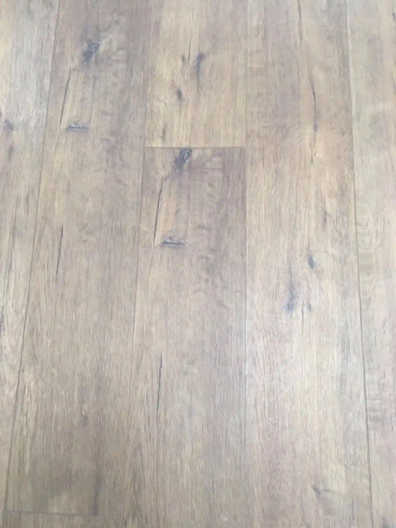 Installed wood-look vinyl plank flooring (SPC / LVT) showing the printed wood-grain decor surface and plank seams of a rigid-core resilient floor