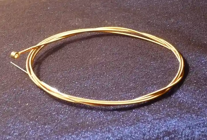 A coiled acoustic guitar string of steel wound with phosphor bronze, a wrought tin bronze alloy, showing the warm golden copper-tin surface